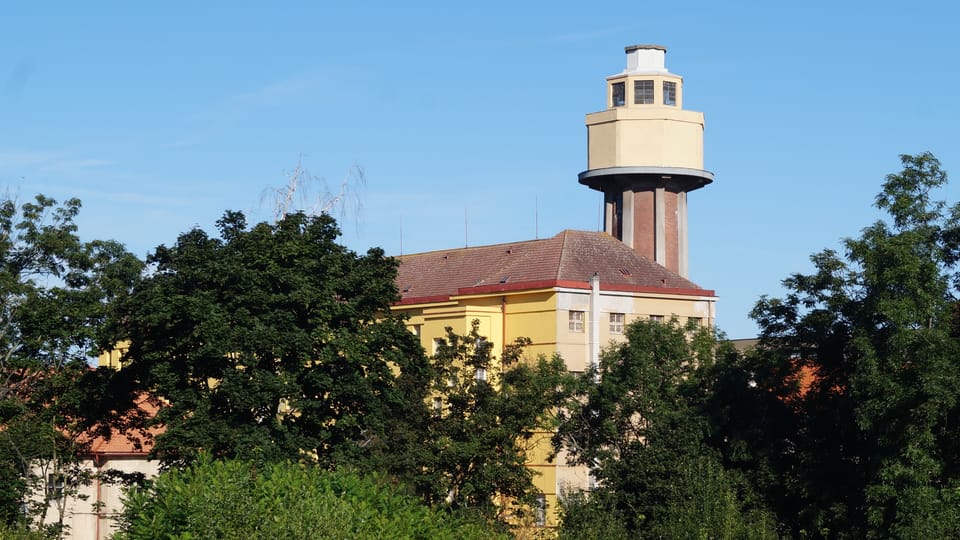 Ruzyňský vodojem je nejvyšší stavbou areálu věznice na západě Prahy. Původní cukrovarský komín byl ve 30. letech obestavěn železobetonovými pilíři, které podpírají nádrž. Měl zároveň sloužit jako strážní věž, ale konstrukční řešení vodojemu to neumožnilo. | Foto: Miloš Turek, Radio Prague International Ruzyňský vodojem je nejvyšší stavbou areálu věznice na západě Prahy. Původní cukrovarský komín byl ve 30. letech obestavěn železobetonovými pilíři, které podpírají nádrž. Měl zároveň sloužit jako strážní věž, ale konstrukční řešení vodojemu to neumožnilo. | Foto: Miloš Turek, Radio Prague International