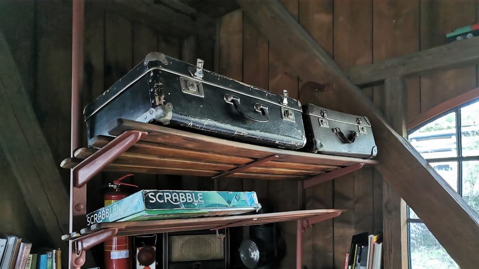 Na policích nad lavicemi ze železničních vagonů jsou dobové předměty i papundeklové kufry | Foto: Petr Lukeš,  Radio Prague International