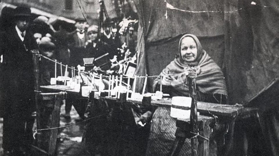 Bába Nájemníková prodává brundibáry a slavíky na vánočním trhu na Staroměstském náměstí,  kolem 1910